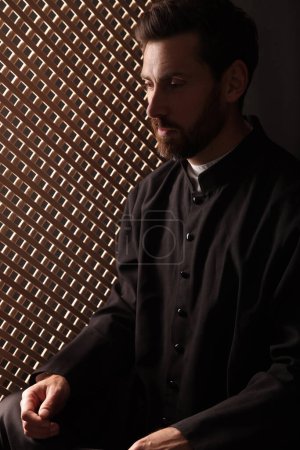 Téléchargez les photos : Prêtre catholique en soutane dans une cabine confessionnelle - en image libre de droit