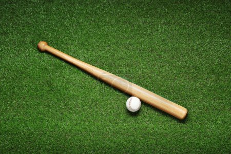 Téléchargez les photos : Wooden baseball bat and ball on green grass, flat lay. Sports equipment - en image libre de droit