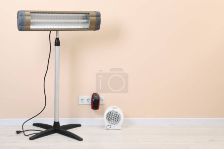 Photo for Different electric heaters near beige wall indoors, space for text - Royalty Free Image