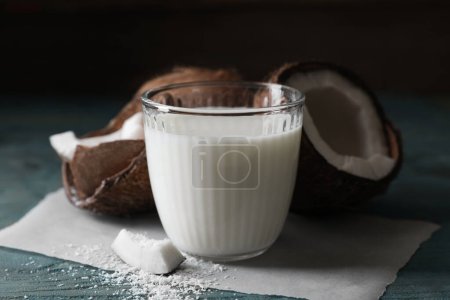 Foto de Vaso de deliciosa leche de coco, hojuelas y nueces sobre mesa de madera - Imagen libre de derechos