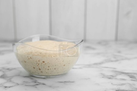 Photo for Leaven in glass bowl on white marble table, space for text - Royalty Free Image