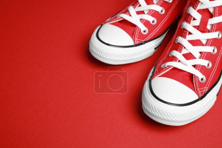Pair of new stylish sneakers on red background, closeup. Space for text