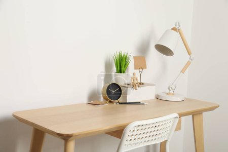 Téléchargez les photos : Lieu de travail confortable avec bureau en bois près du mur blanc - en image libre de droit