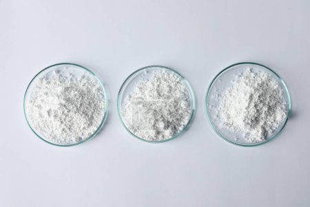 Petri dishes with calcium carbonate powder on white table, flat lay