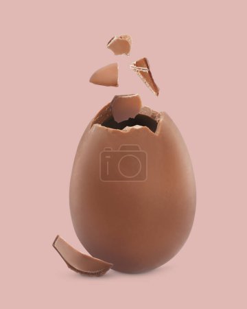 Photo for Exploded milk chocolate egg on dusty pink background - Royalty Free Image