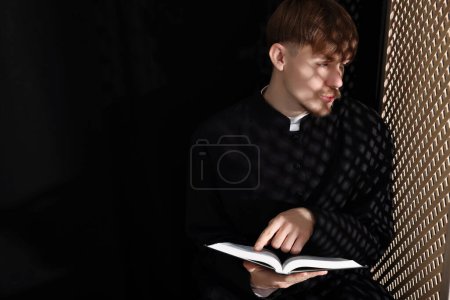 Foto de Sacerdote católico con Biblia hablando con el feligrés en confesionario. Espacio para texto - Imagen libre de derechos