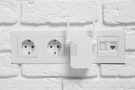 Téléchargez les photos : Répéteur Wi-Fi sans fil sur mur de briques blanches - en image libre de droit