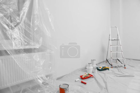 Foto de Escalera plegable metálica y herramientas de pintura en interiores, espacio para texto - Imagen libre de derechos