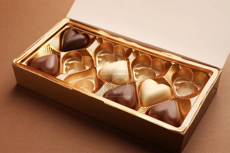 Caja parcialmente vacía de caramelos de chocolate sobre fondo marrón, primer plano