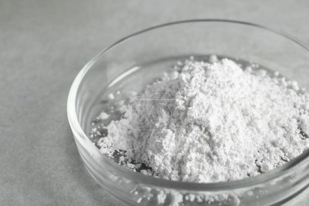 Petri dish with calcium carbonate powder on light grey table, closeup