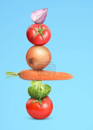 Stack of different fresh vegetables on light blue background