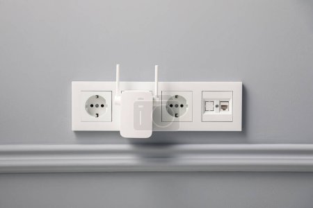 Photo for Wireless Wi-Fi repeater on light grey wall - Royalty Free Image