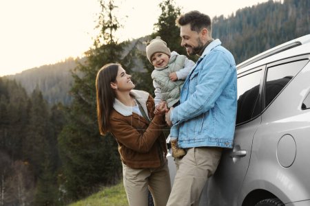 Foto de Los padres y su hija cerca del coche en las montañas. Viajes en familia - Imagen libre de derechos