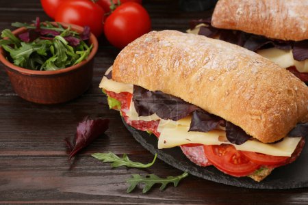 Foto de Deliciosos sándwiches con queso, salami, tomate sobre mesa de madera, primer plano - Imagen libre de derechos
