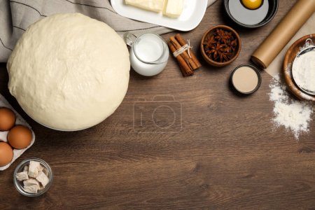 Flat lay composition with fresh yeast dough and different ingredients on wooden table, space for text. Making cake