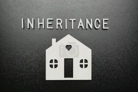Photo for Word Inheritance made with white letters and house model on black background, flat lay - Royalty Free Image