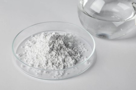 Foto de Placa Petri con polvo de carbonato de calcio y matraz de laboratorio sobre mesa blanca - Imagen libre de derechos