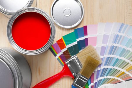 Photo for Can of red paint, closed ones, brushes and palette on wooden table, flat lay - Royalty Free Image