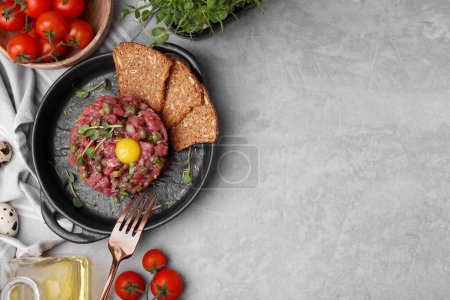 Photo for Tasty beef steak tartare served with yolk, capers and other accompaniments on light grey table, flat lay. Space for text - Royalty Free Image