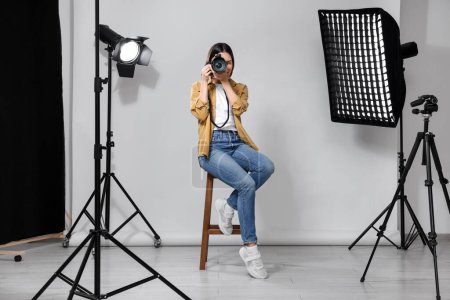 Professional photographer with camera in modern photo studio