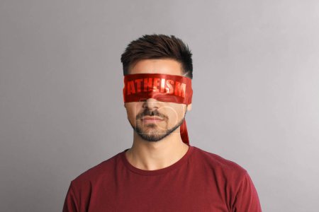 Photo for Man wearing red blindfold with word Atheism on light grey background - Royalty Free Image