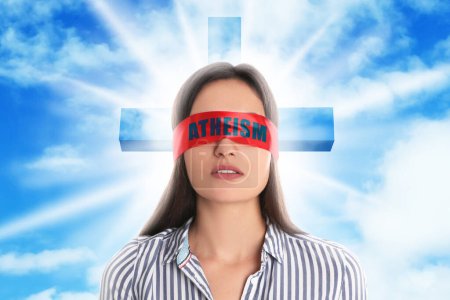 Photo for Woman wearing red blindfold with word Atheism, sky with clouds and silhouette of cross on background - Royalty Free Image