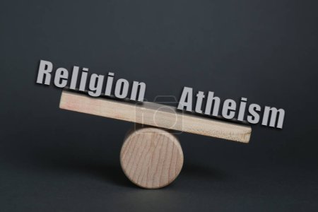 Téléchargez les photos : Choix entre athéisme et religion. Scie à sous-bois miniature avec mots sur fond gris foncé - en image libre de droit