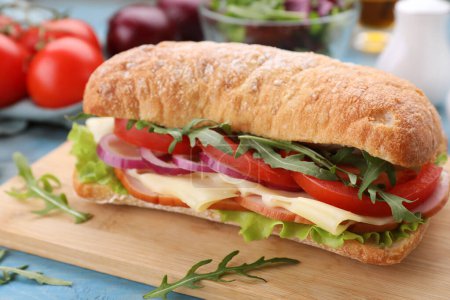 Foto de Delicioso sándwich con verduras frescas, queso y rúcula sobre tabla de madera, primer plano - Imagen libre de derechos