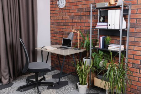 Téléchargez les photos : Lieu de travail élégant avec bureau, chaise, bibliothèque et plantes en pot à la maison - en image libre de droit