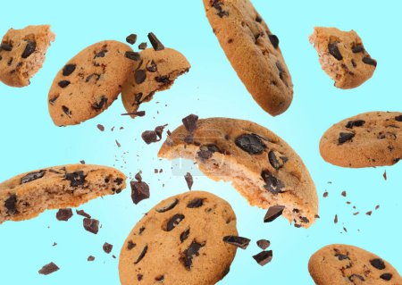 Tasty chocolate chip cookies falling on light blue background