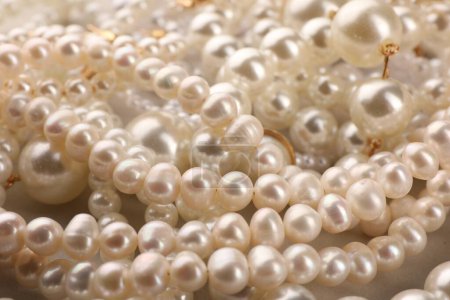 Elegant pearl necklaces as background, closeup view