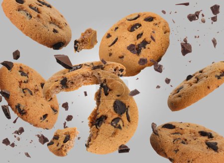 Tasty chocolate chip cookies falling on light grey background