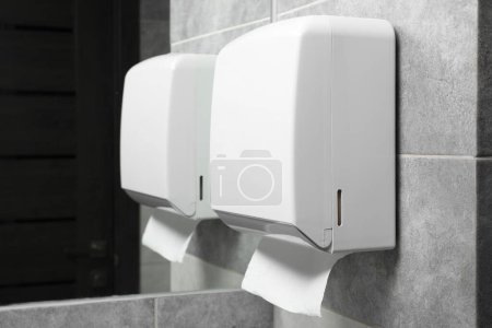 Photo for New paper towel dispenser hanging on wall near mirror in bathroom - Royalty Free Image