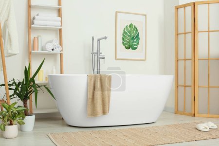 Téléchargez les photos : Élégant intérieur de salle de bain avec belle baignoire et plantes d'intérieur - en image libre de droit