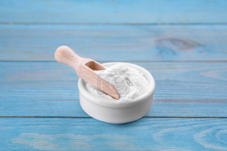 Bowl of fructose powder on light blue wooden table