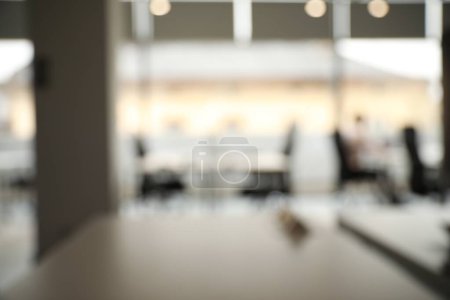 Vista borrosa de los acogedores espacios de trabajo con mesas y sillas en la oficina