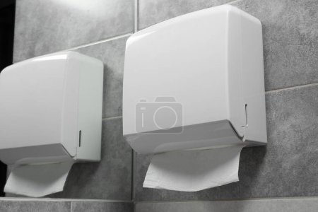 Photo for New paper towel dispenser hanging on wall near mirror in bathroom - Royalty Free Image