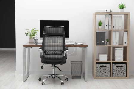 Téléchargez les photos : Cozy workspace with computer on desk, chair and bookcase near white wall at home - en image libre de droit