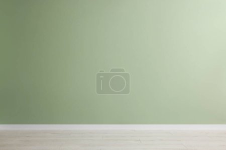 Chambre vide avec mur vert et plancher en bois
