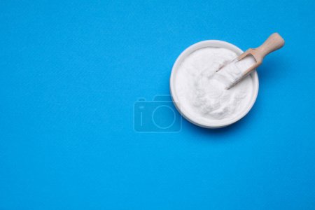 Photo for Bowl of sweet powdered fructose on light blue background, top view. Space for text - Royalty Free Image
