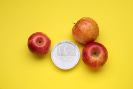 Foto de Fructosa dulce en polvo y manzanas sobre fondo amarillo, plano - Imagen libre de derechos