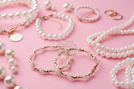 Elegant pearl jewelry on pink background, closeup