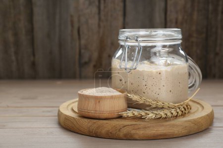 Photo for Leaven and ears of wheat on beige wooden table, space for text - Royalty Free Image