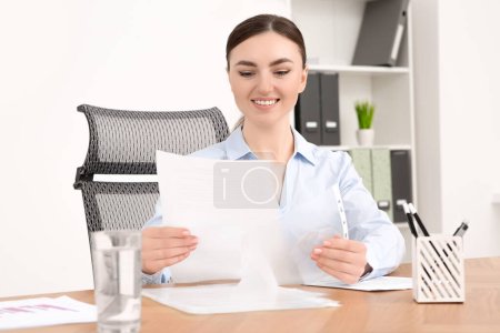 Geschäftsfrau arbeitet an Holztisch im Büro mit Dokumenten
