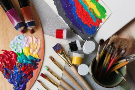 Foto de Artist's palette with mixed bright paints and brushes on textured table, flat lay - Imagen libre de derechos