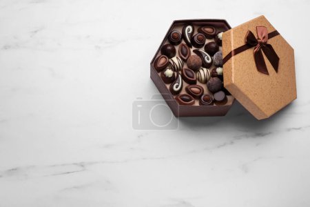 Photo for Open box of delicious chocolate candies on white marble table, top view. Space for text - Royalty Free Image