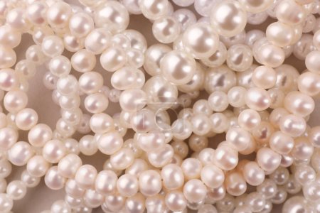 Elegant pearl necklaces as background, top view