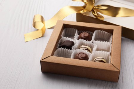 Photo for Partially empty box of chocolate candies on white wooden table - Royalty Free Image