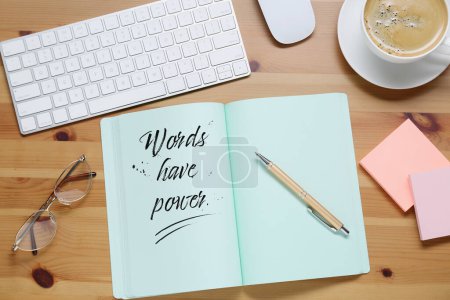 Photo for Open notebook with phrase Words Have Power and pen on wooden table, flat lay. Workplace with cup of coffee - Royalty Free Image