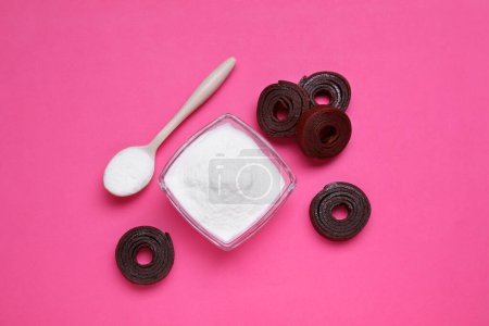 Photo for Sweet powdered fructose and fruit leather rolls on pink background, flat lay - Royalty Free Image